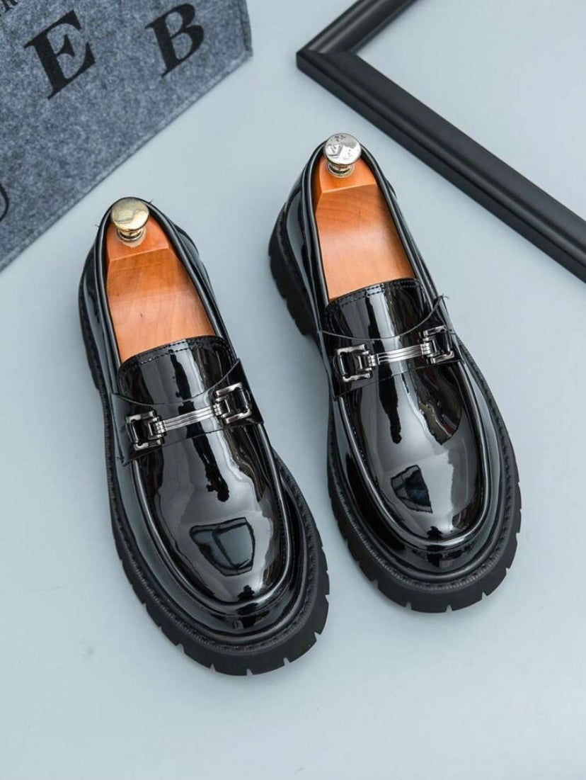 Mocassins habillés pour homme en noir et blanc avec finition brillante et pampilles décoratives, parfaits pour un style professionnel raffiné.