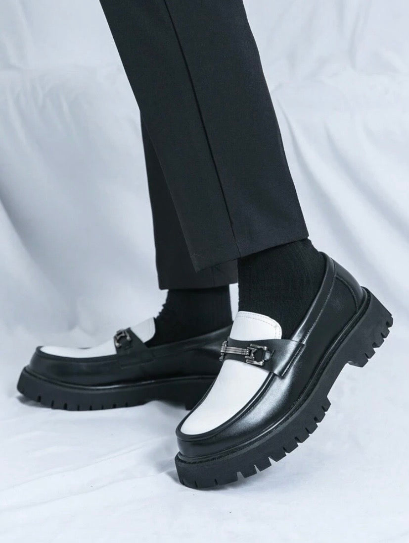 Mocassins habillés pour homme en noir et blanc avec finition brillante et pampilles décoratives, parfaits pour un style professionnel raffiné.