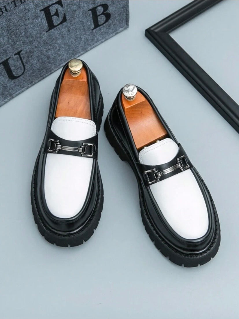 Mocassins habillés pour homme en noir et blanc avec finition brillante et pampilles décoratives, parfaits pour un style professionnel raffiné.